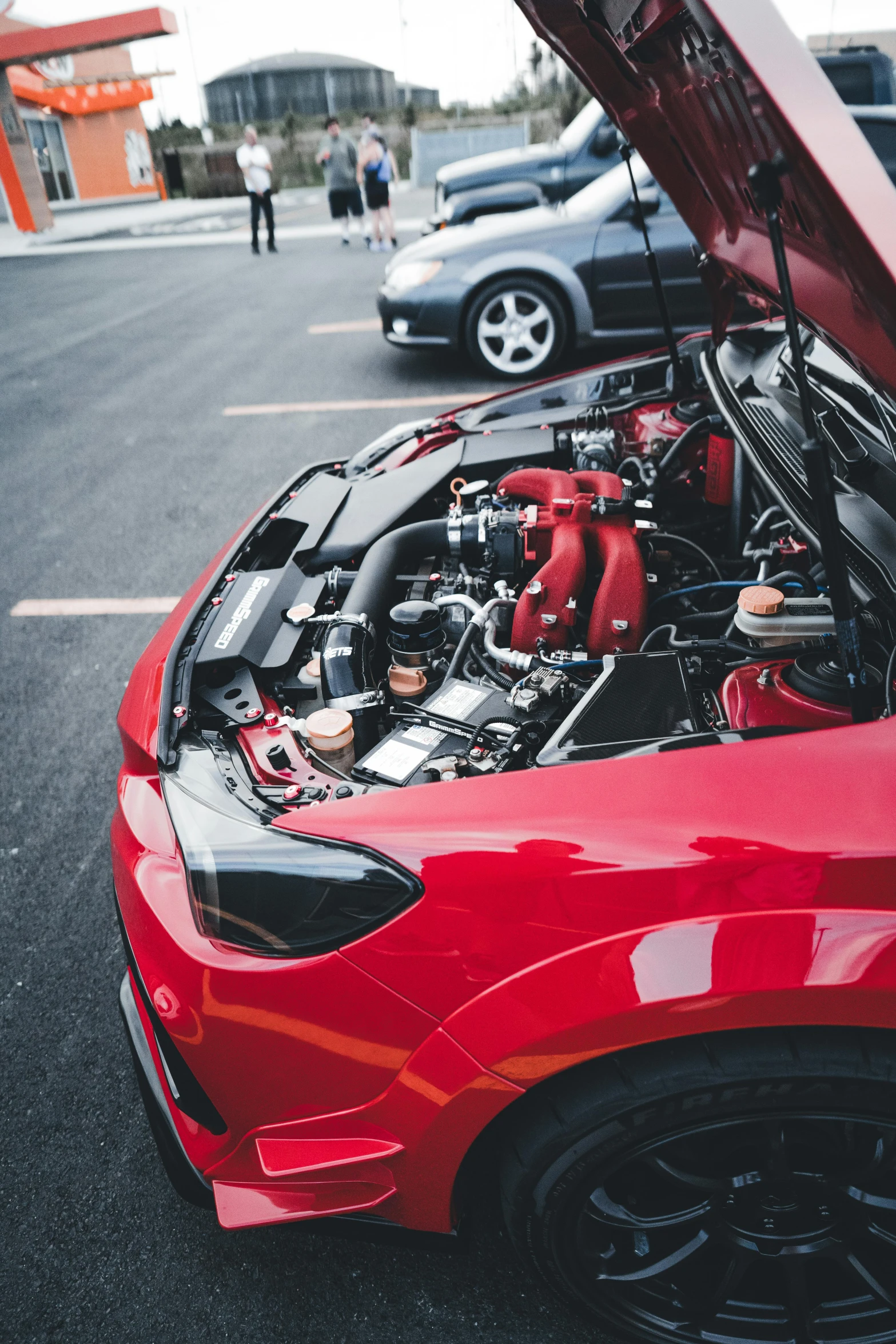 a car with the hood up showing a red car engine