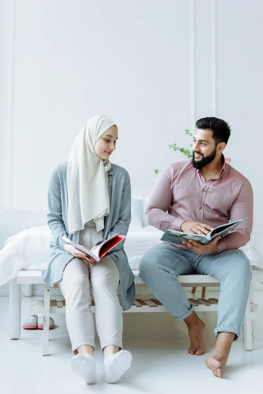 two people are sitting on a bed with books