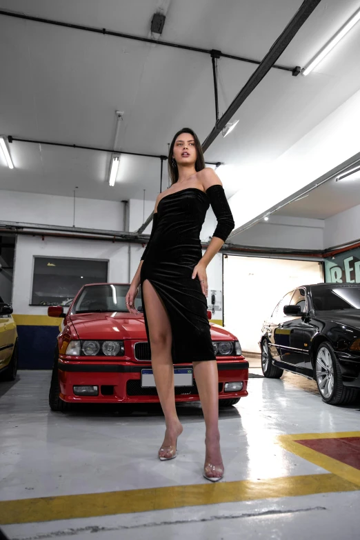 a woman in a long dress standing next to two parked cars