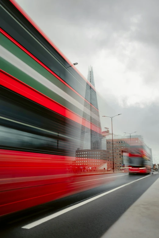 double decker bus with red, green and white stripes coming down a street