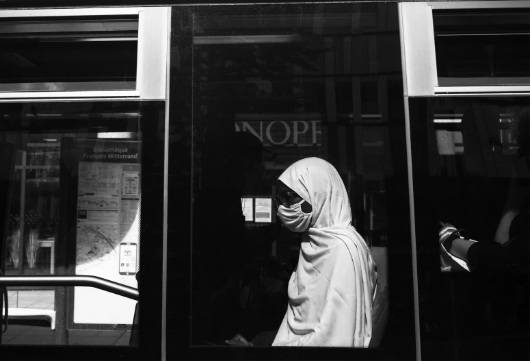 a woman in a veil wearing head covering looking through a window