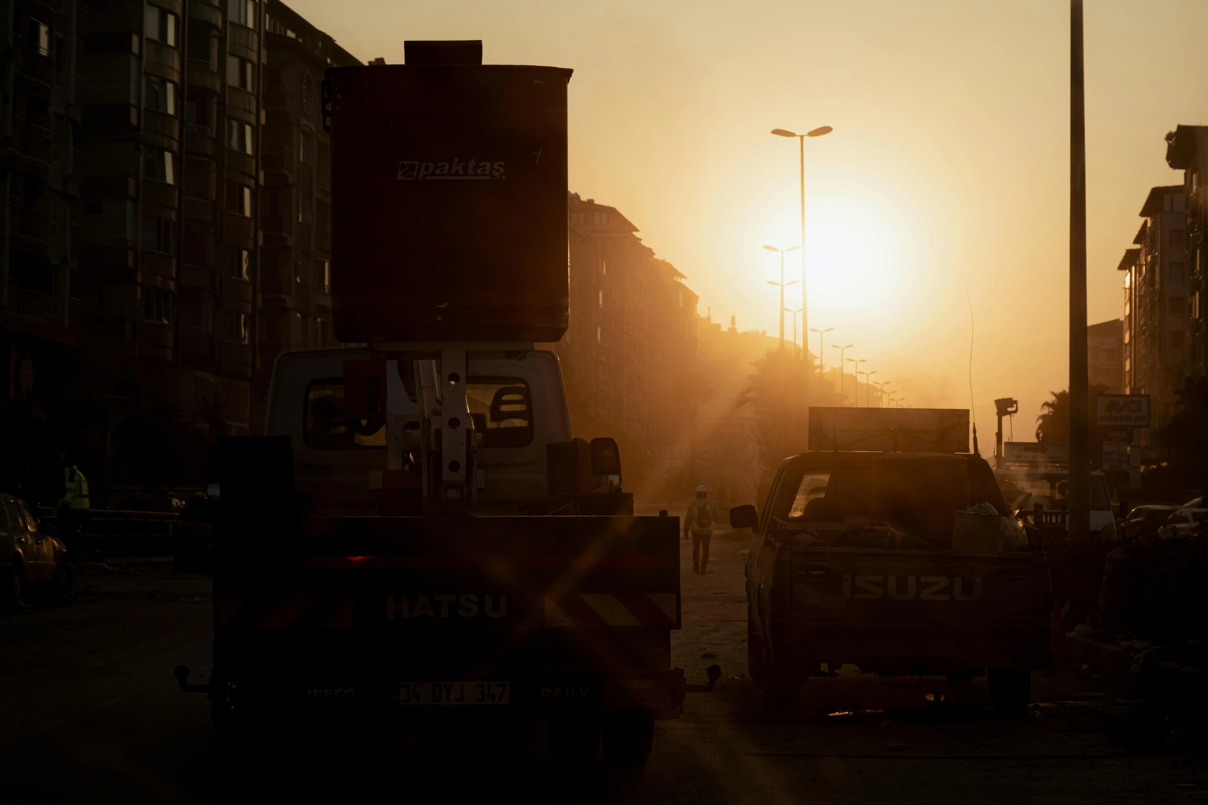 a road and traffic at sunset with two dump trucks on the side