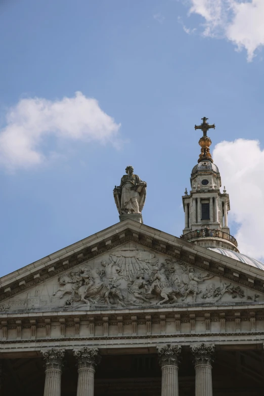 the top of a building with two statues and a cross