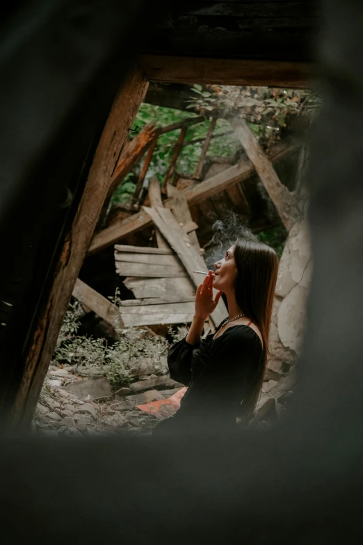 woman sitting outside smoking a cigarette in a forest