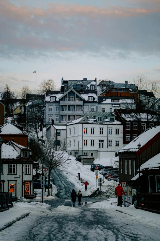 a few people walk down a snowy street