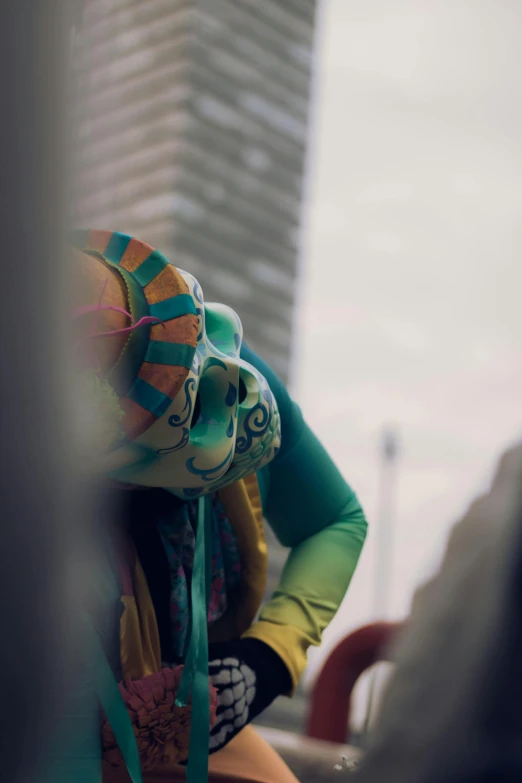 a clown mask sitting next to a man in front of tall buildings