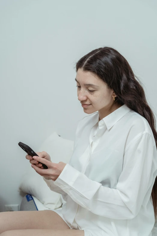 a woman in white shirt looking at a cell phone