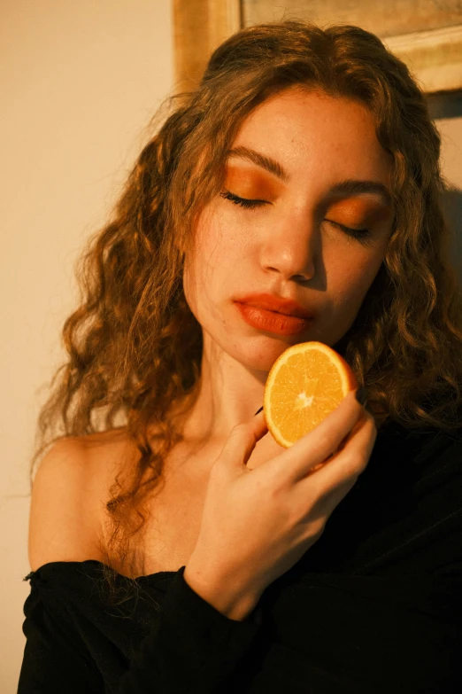 a woman with long curly hair is holding a orange