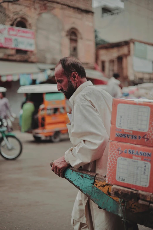 the man is standing in the street with a cart full of boxes