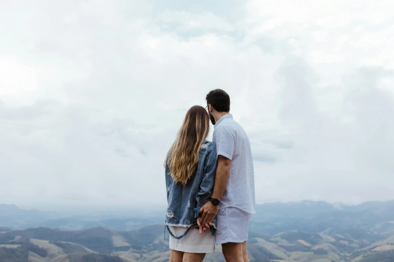 couple in white outfits looking over a large open valley