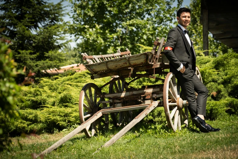 a man leaning on a old wooden cart in the middle of a field