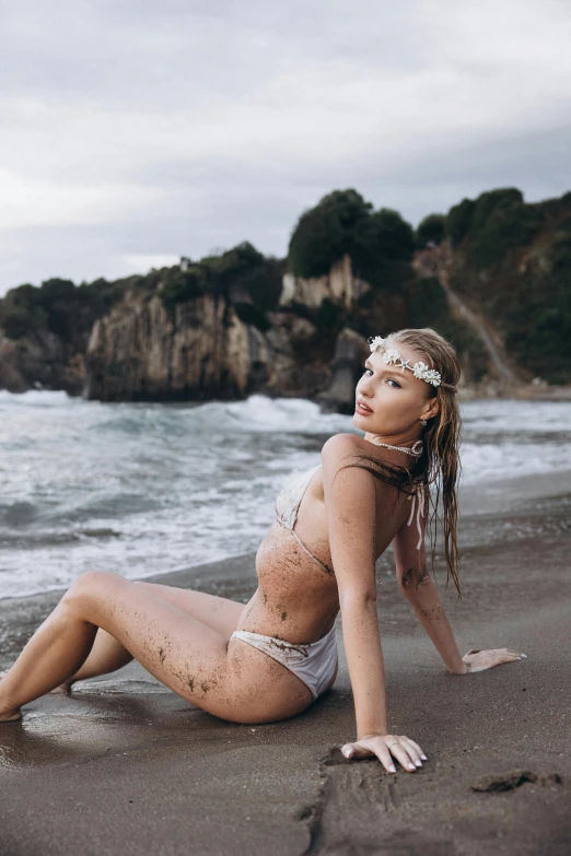 an  woman is laying on a beach with water in the background