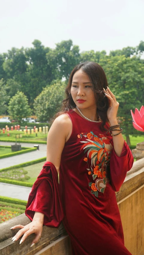 young woman wearing a burgundy dress posing by the gardens