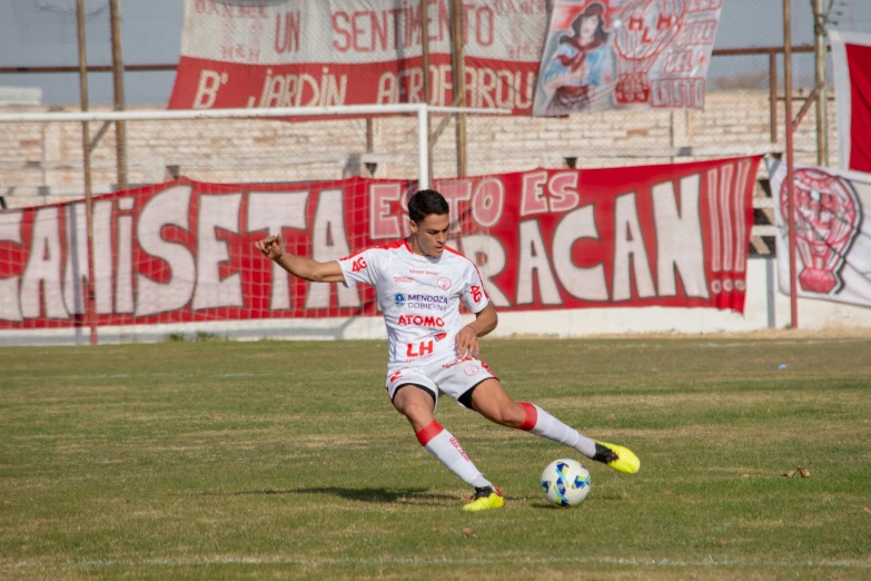 a man kicking a soccer ball on top of a field