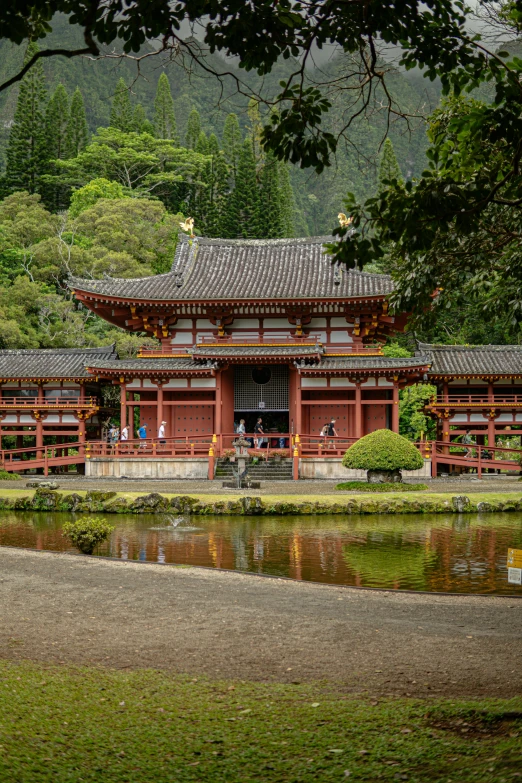 people sitting at a bench in the background of a building with water surrounding