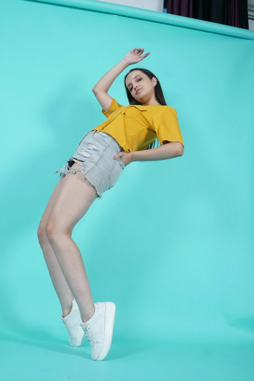 a woman wearing high heeled shoes and a yellow shirt posing with her arms raised in the air