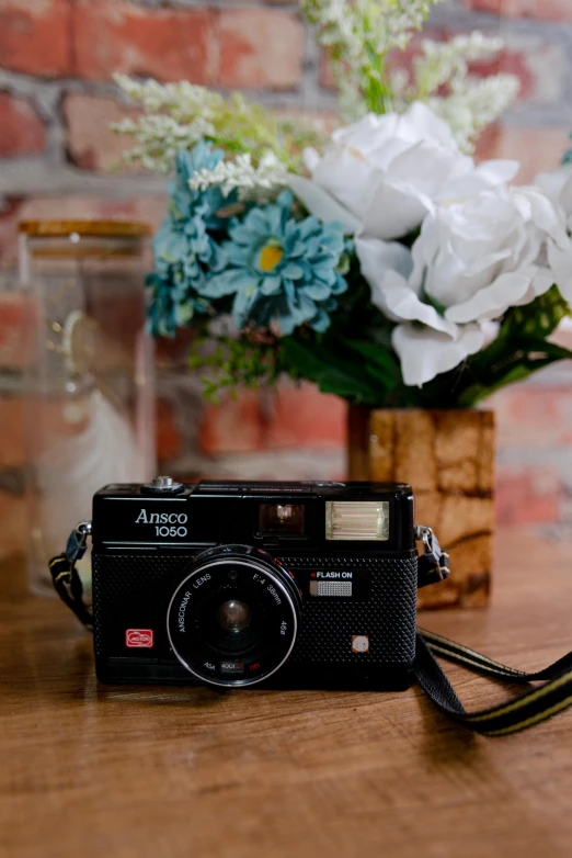 a camera next to a vase with white flowers in it