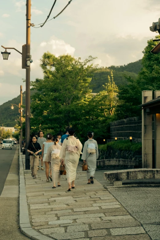 several people walking down the sidewalk near a stoplight