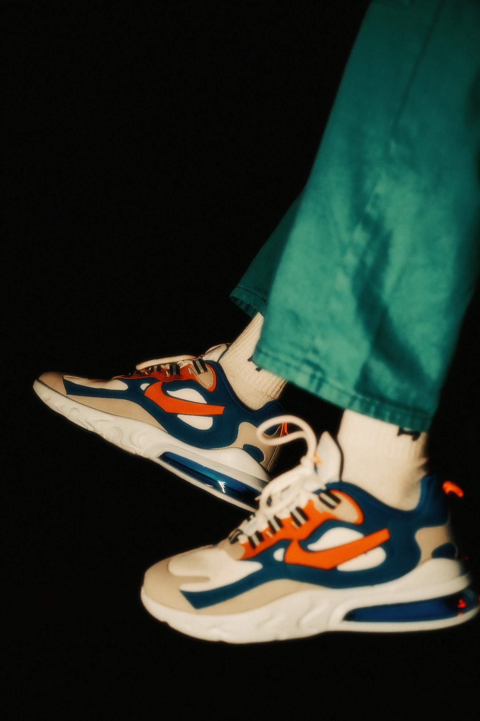 a close up image of a person's shoes, wearing green pants and white sneakers