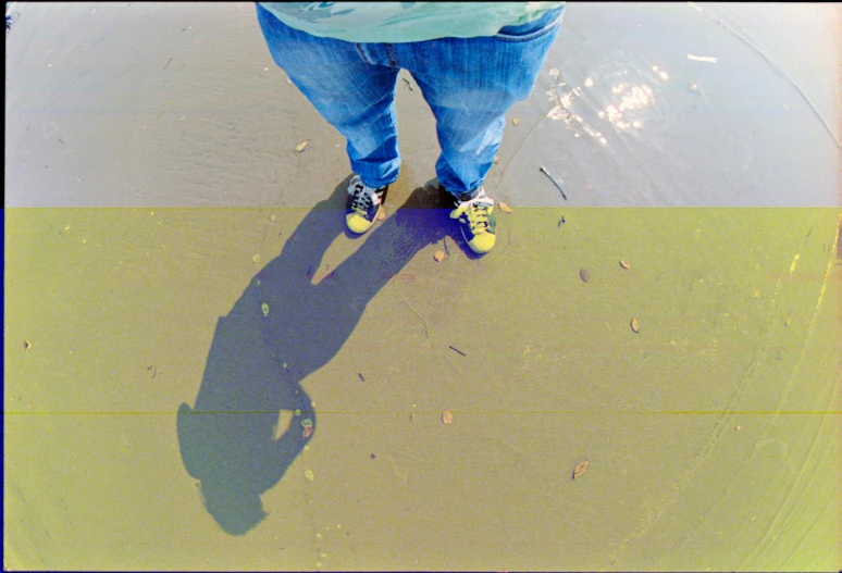 the shadow of someone standing on concrete and holding a skateboard