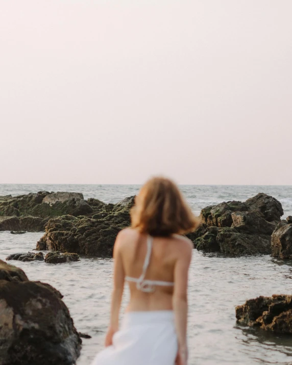 a woman in a white dress standing by the water