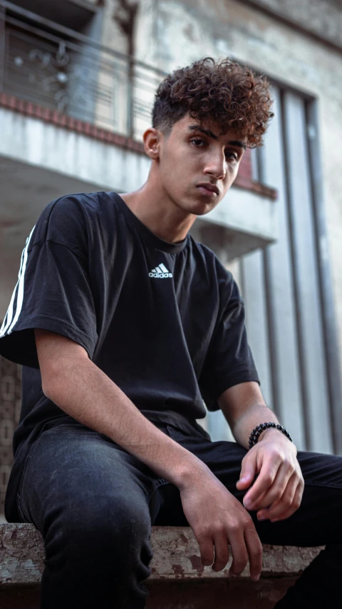 a young man sitting on the ledge of a building