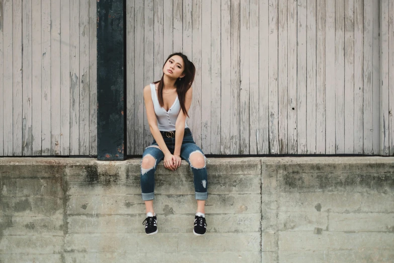 a young woman sitting on a ledge in front of a building