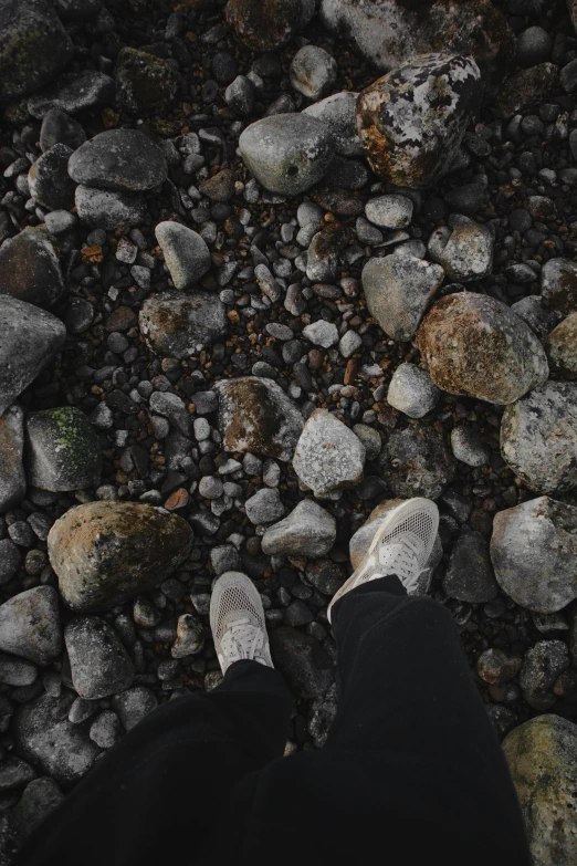 the feet of someone who is standing on a rocky surface