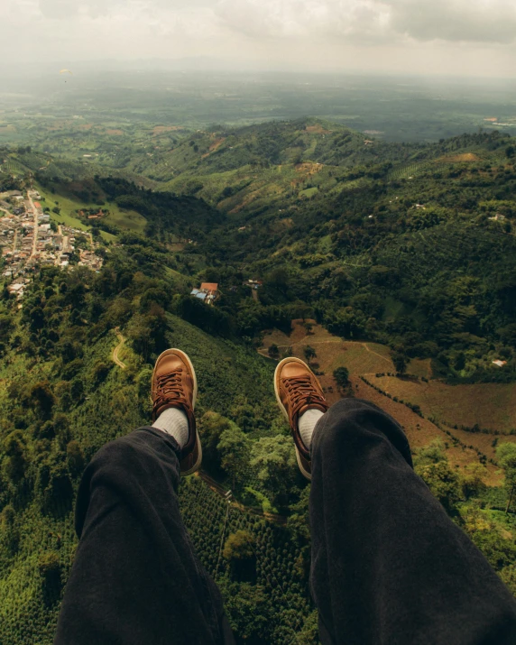 a view from the top of a hill of a person's shoes looking out at the town below