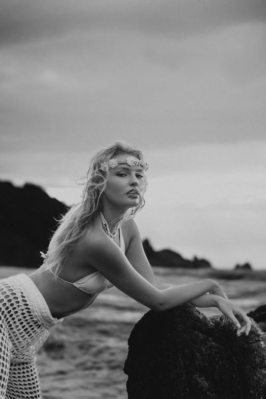 a woman on a rocky beach in black and white