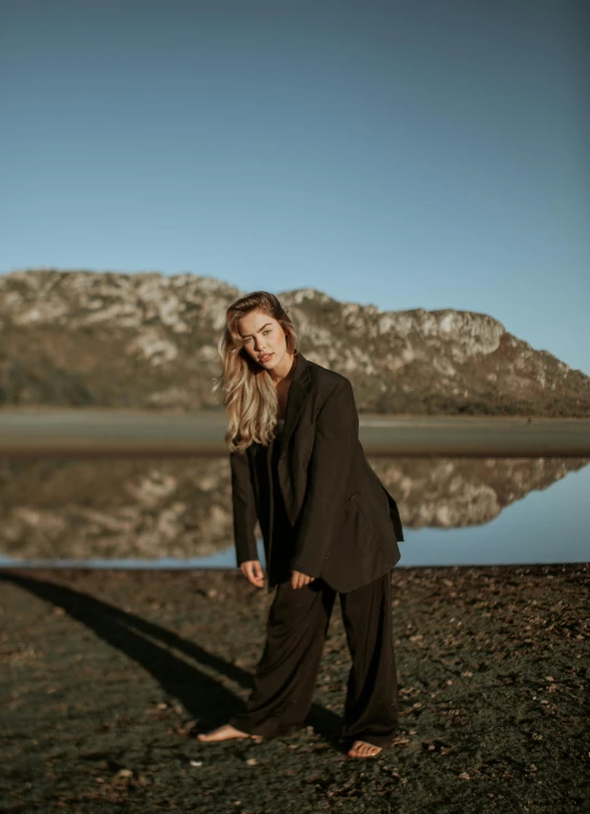 a woman stands near the water and poses for a picture