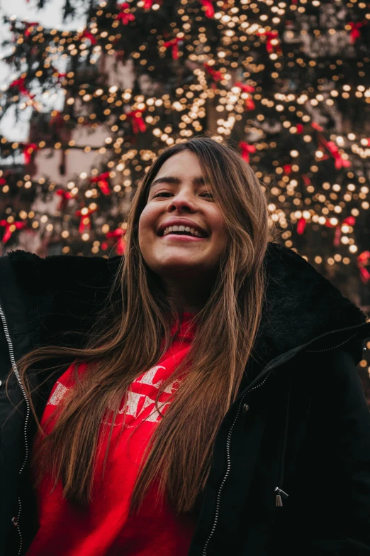 a woman standing in front of a christmas tree