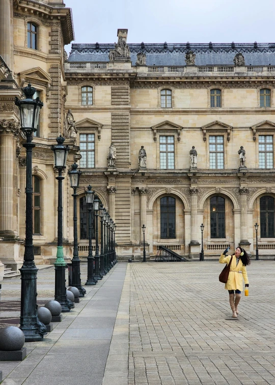 a woman in a yellow dress walking past a large building