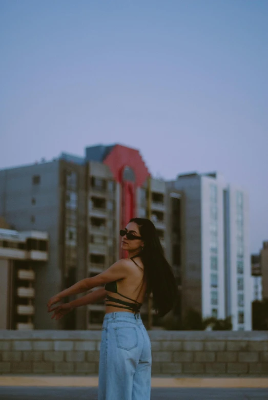 a woman wearing a pair of jeans, in front of some buildings