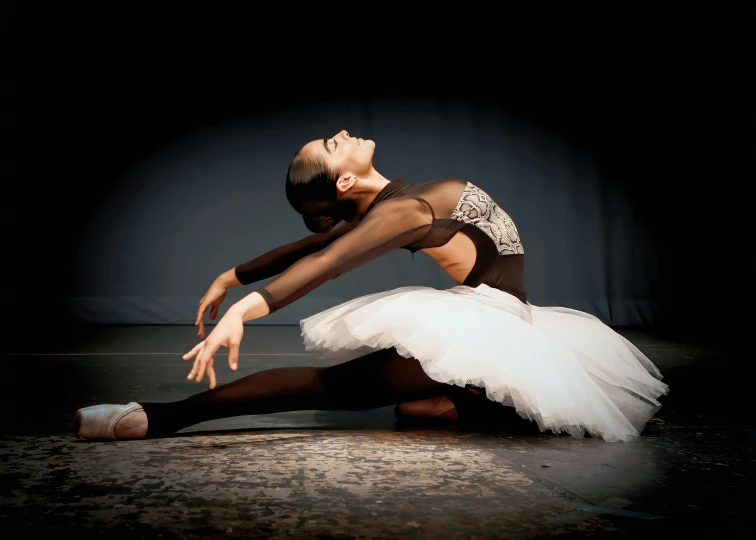 a young ballerina is stretching for a po