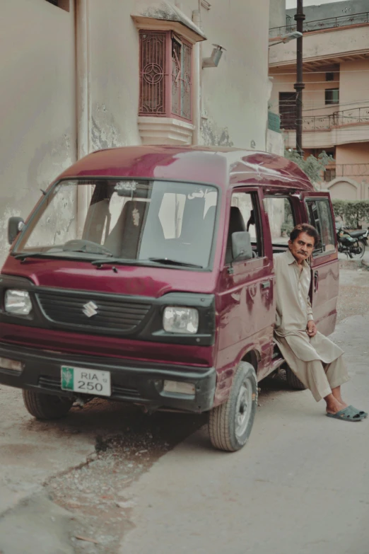 a man sitting in front of a van and on the street