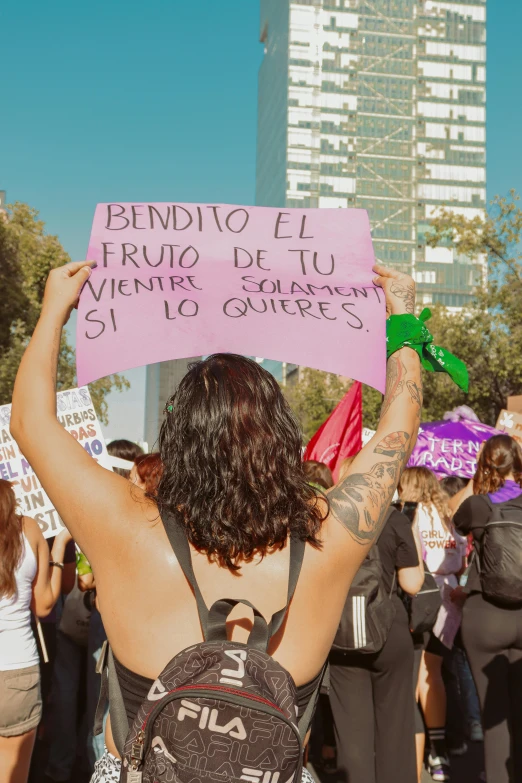 a woman holding up a pink sign with writing