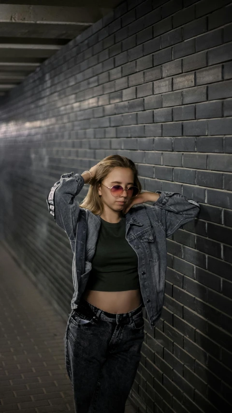 a woman in black top standing by brick wall