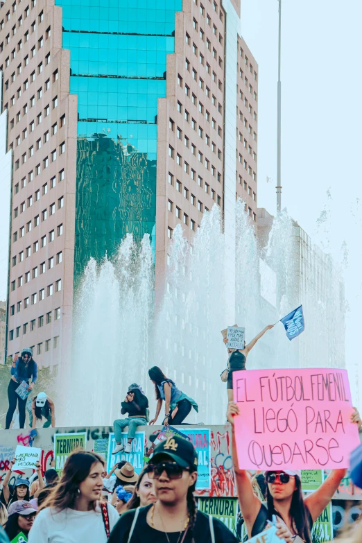 people holding signs near a fountain and a blue building