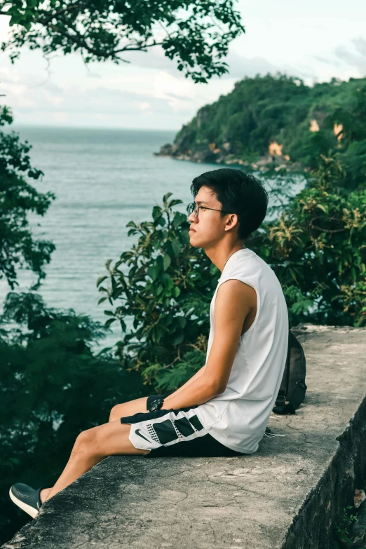 a man sitting on the edge of a balcony near water