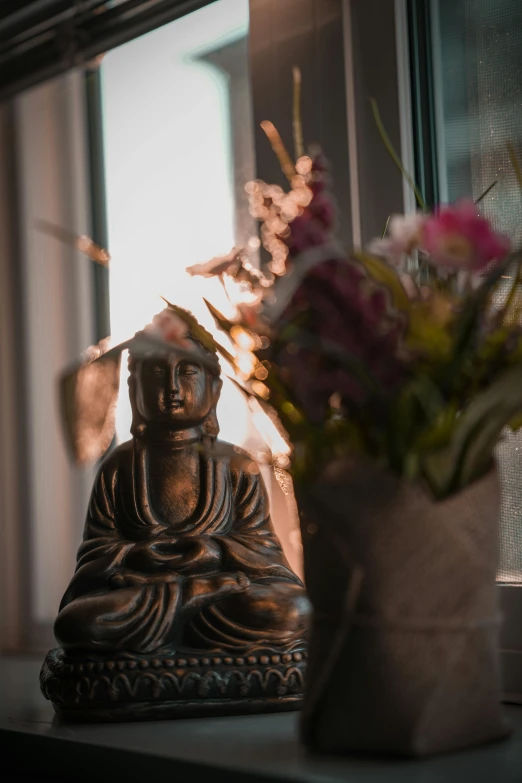 a wooden buddha figure and a vase with flowers