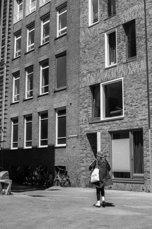 a woman in front of a brick building with bicycles parked nearby