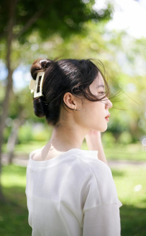 a woman is standing in the grass with her hair pinned back