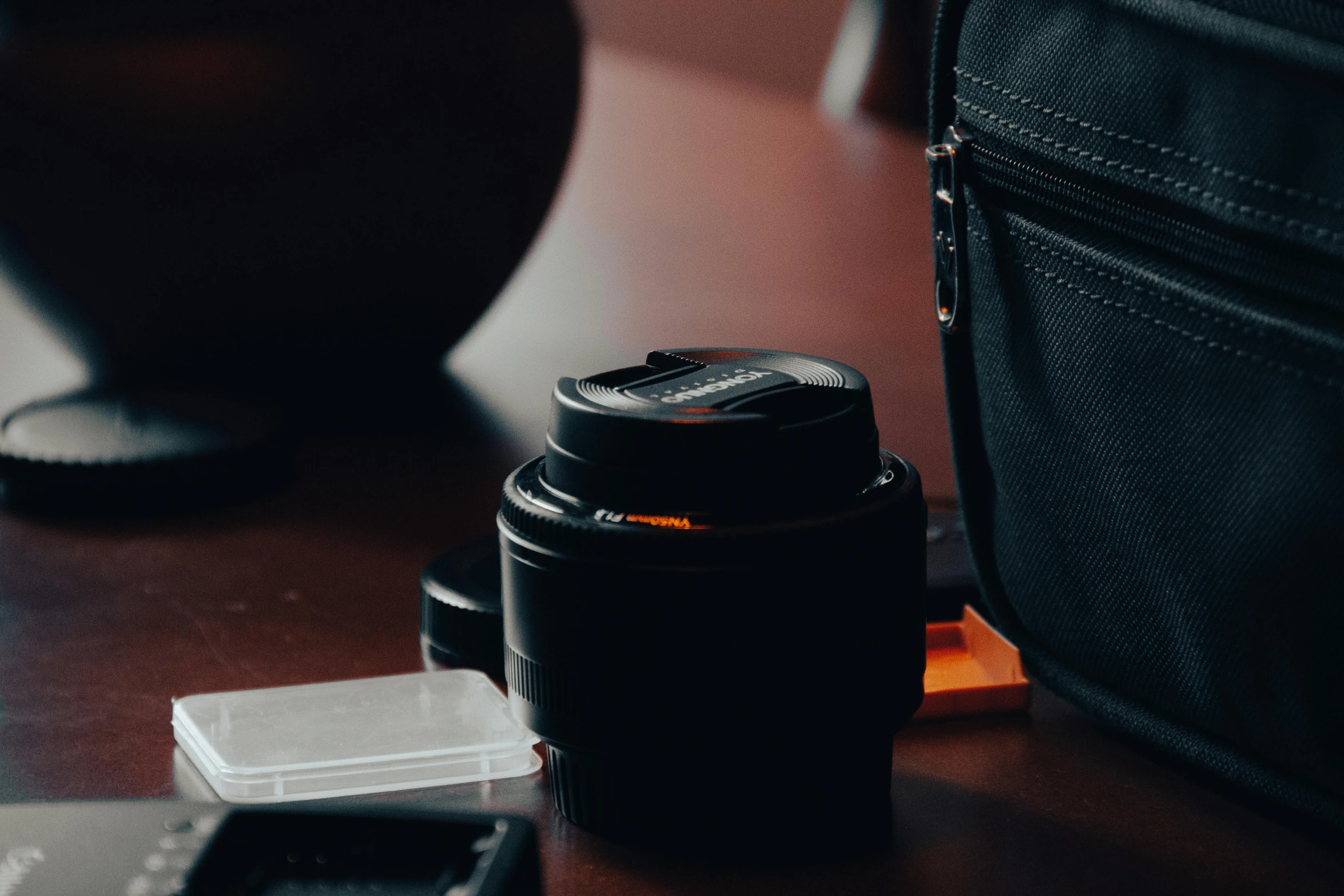 camera and lens cap on a table in front of a cell phone