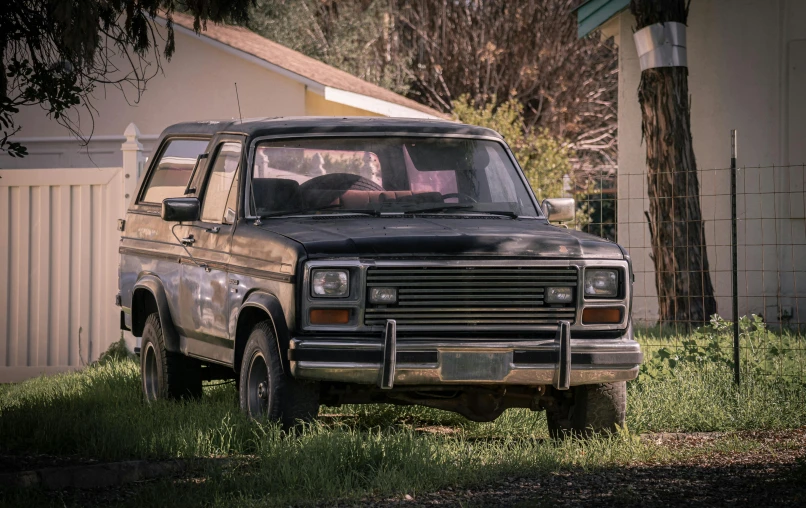 an old truck in the grass with a window