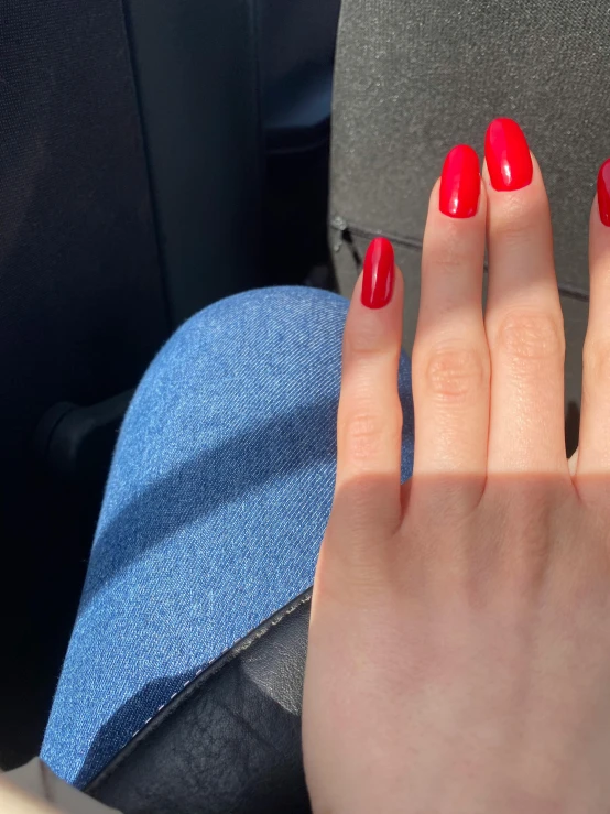 someone in a car has a bright red manicure