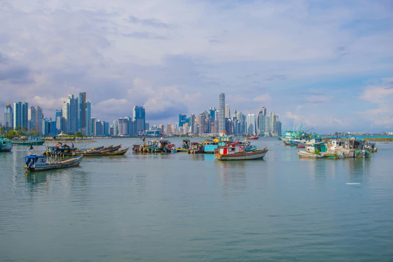 several boats sit in the ocean in front of a city skyline