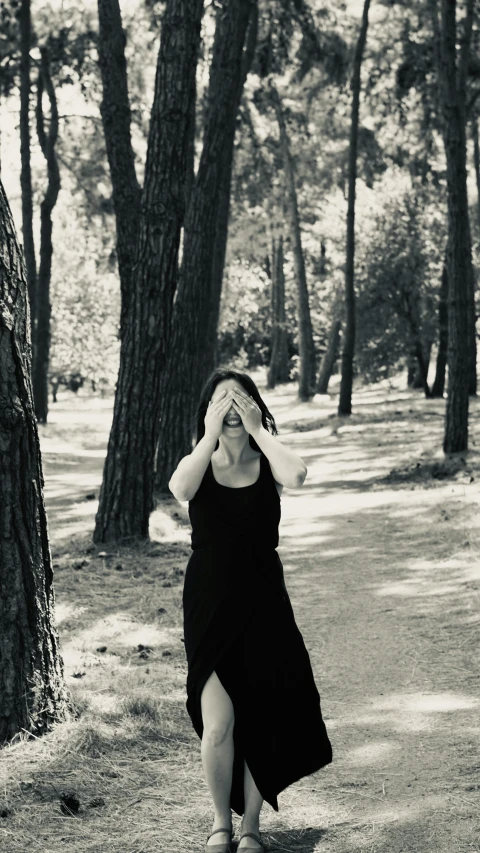 a woman is in the woods and is holding her head with her hands