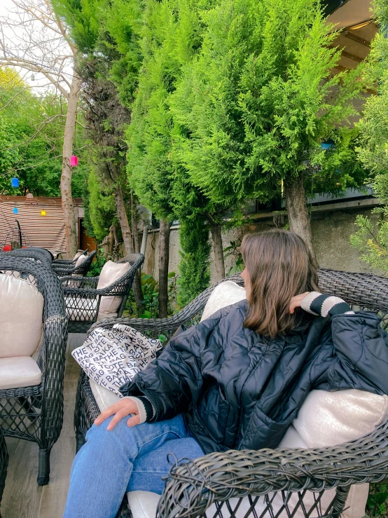 a woman sitting on top of a chair in front of trees