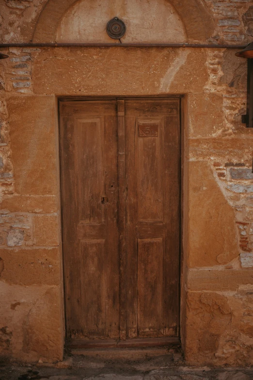 the old door is open in front of the stone wall